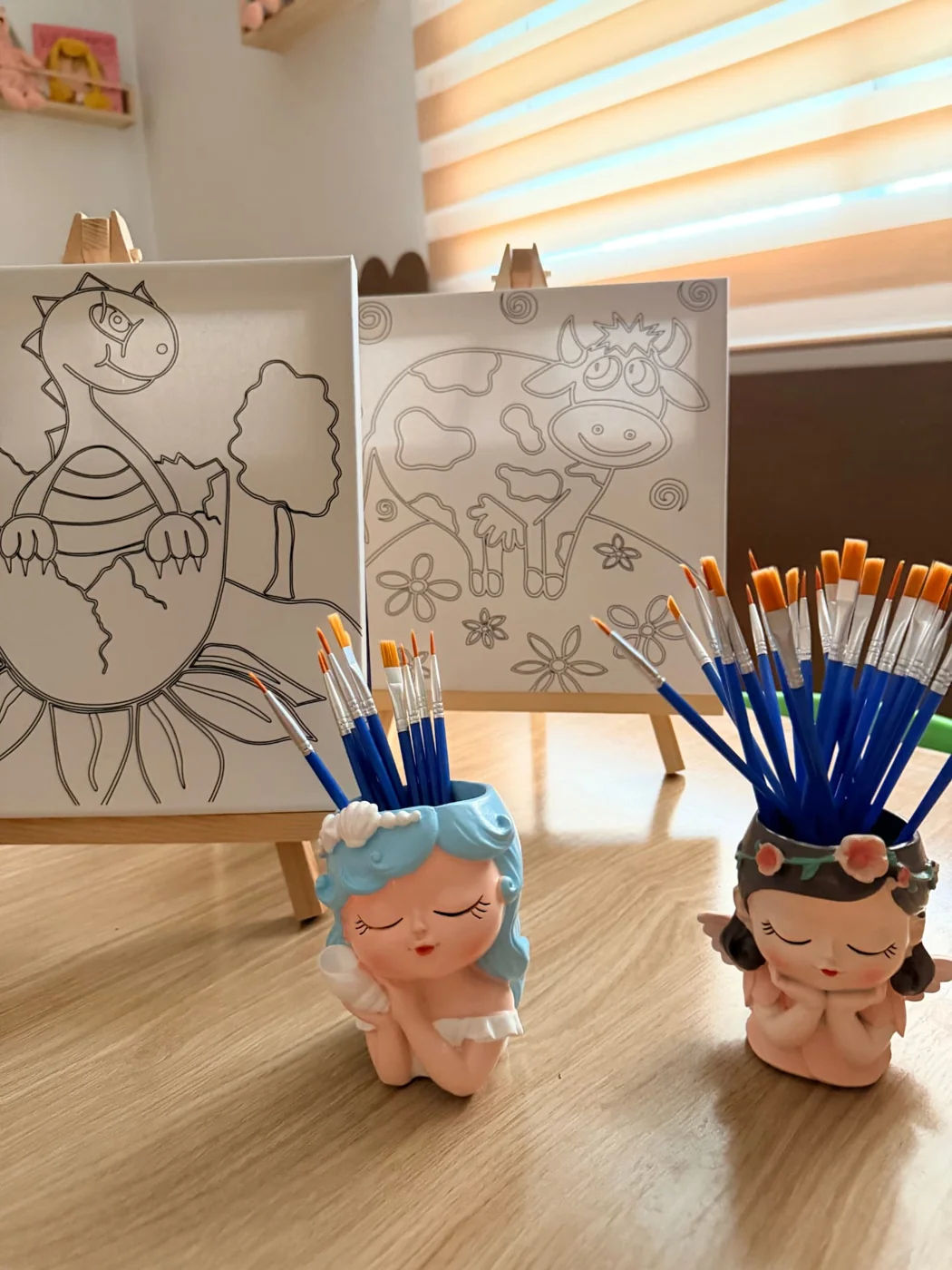 Chevalets en bois avec toiles à colorier et pots de pinceaux