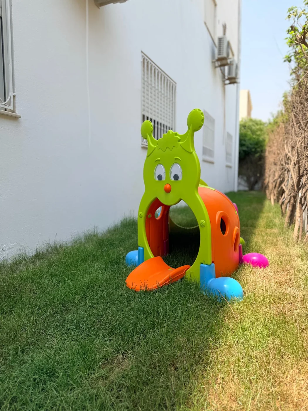 Tunnel de jeu vert et orange sur le gazon le long du bâtiment