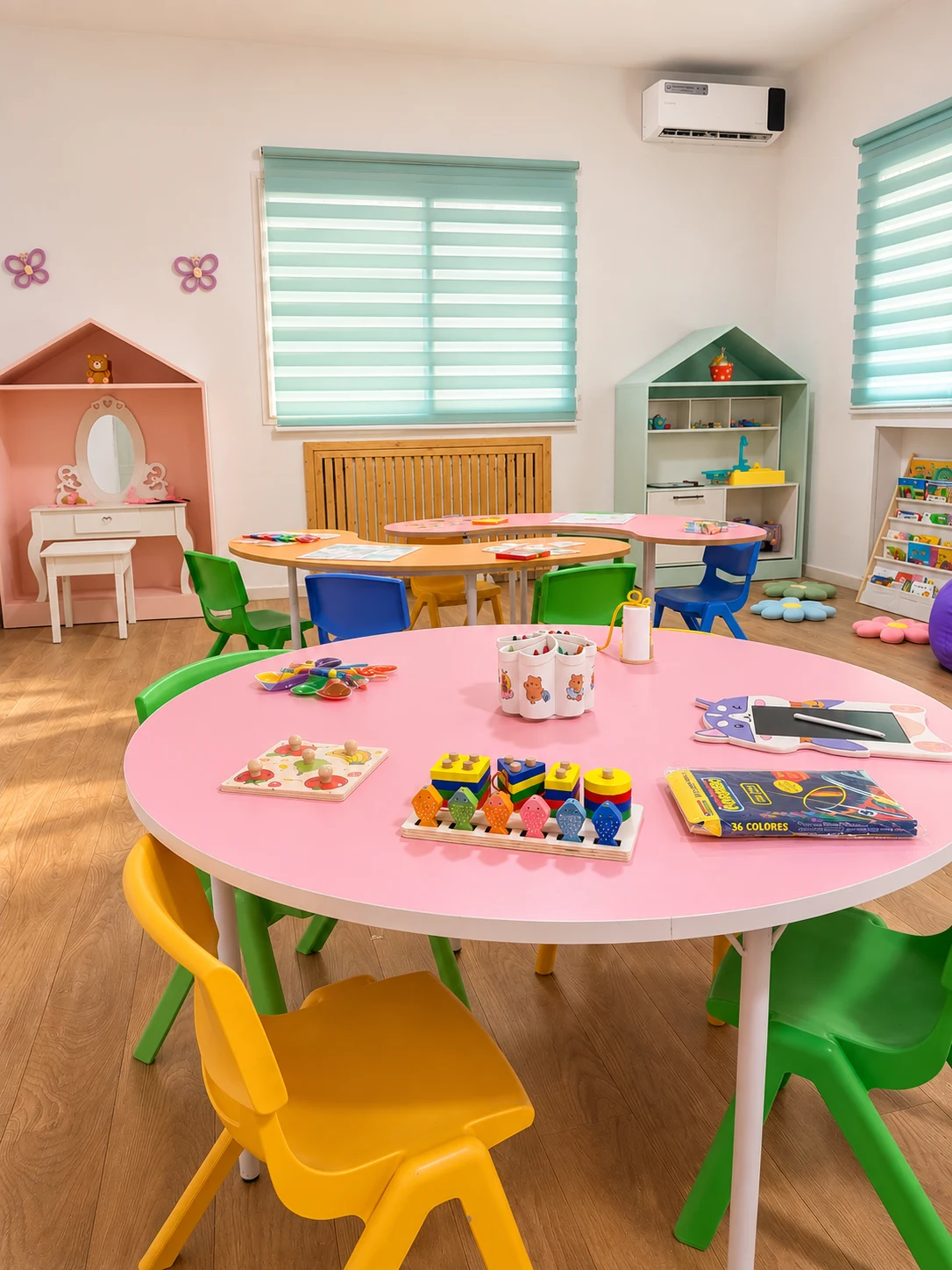 Salle de classe MyDream avec tables rondes roses, chaises colorées, maisonnettes de jeu et bibliothèque