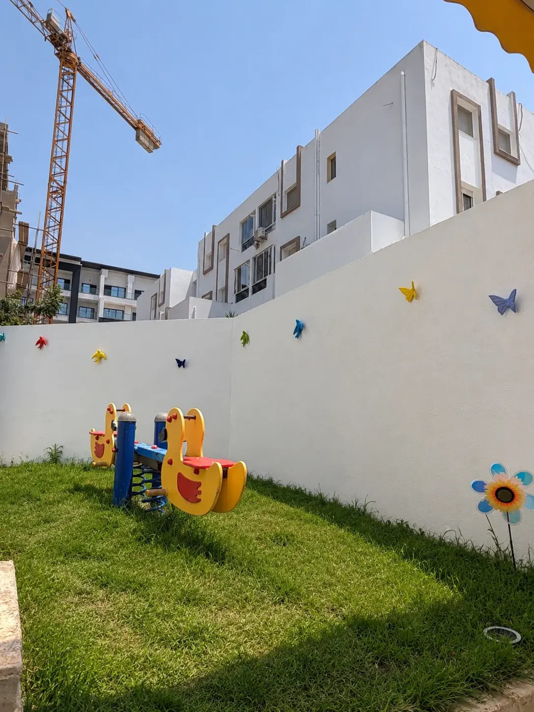 Jeux à ressort colorés sur le gazon devant un mur blanc décoré