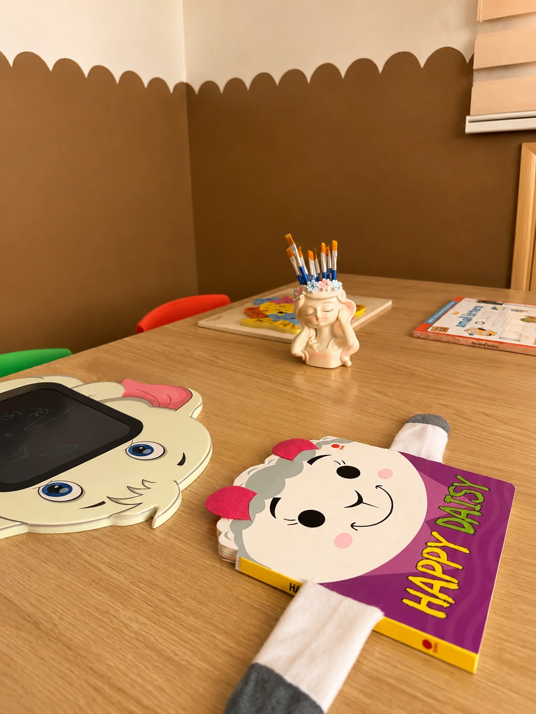 Table en bois avec livre illustré, ardoise de dessin en forme d'animal, puzzle et pot de pinceaux